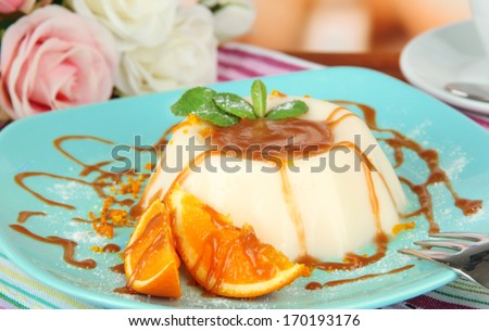 Panna Cotta with orange zest and caramel sauce, on color wooden background
