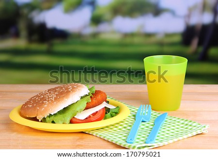 Tasty sandwich with cutlet on color  plastic plate on bright background