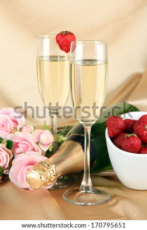 Romantic still life with champagne, strawberry and pink roses, on color fabric background