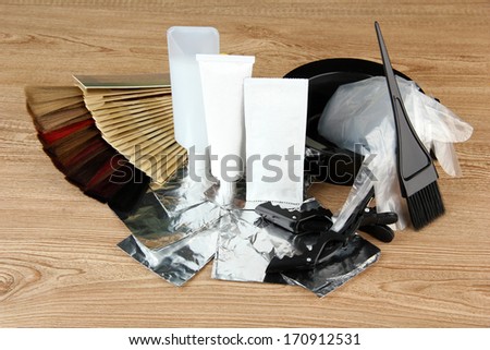 Hair dye kit and hair samples of different colors, on wooden background