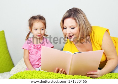 Little girl with mom read book in bed