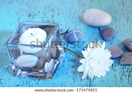 Decorative vase with candle, water and stones on wooden table close-up