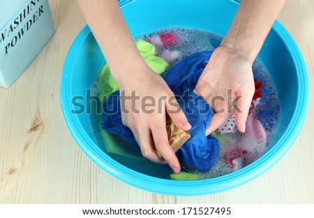 Hand washing in plastic bowl on wooden table close-up