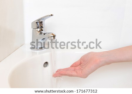 Close-up of human hands being washed under faucet in bathroom, isolated on white