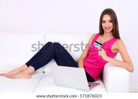 Beautiful young woman sitting on sofa  with laptop on white background