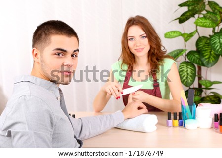 Beautiful girl manicurist doing manicure for man in beauty salon