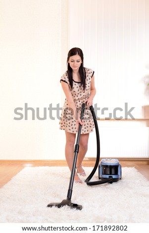 Beautiful young woman with vacuum cleaner in room