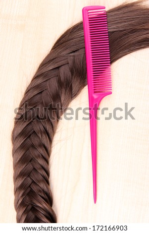 Long brown hair with comb on wooden background