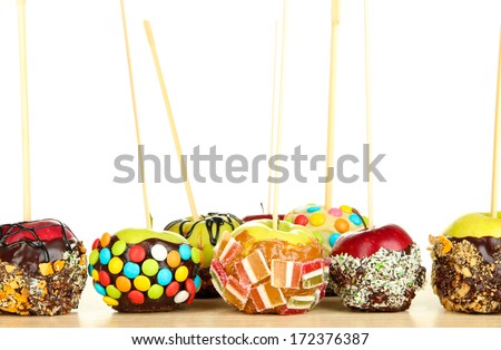 Candied apples on sticks on wooden table on white background