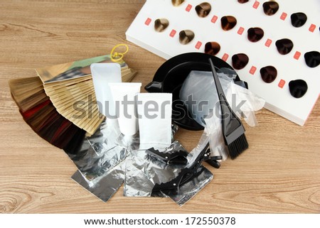 Hair dye kit and hair samples of different colors, on wooden background