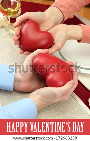 hands of romantic couple with hearts over a restaurant table