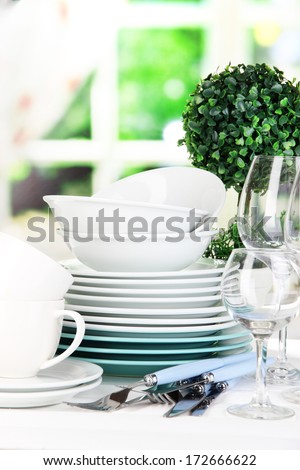 Clean dishes on table on window background