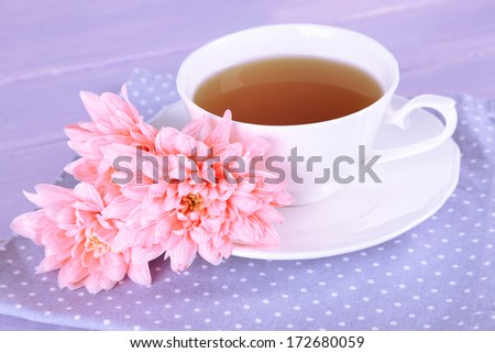 Pink chrysanthemums and cup of tea on wooden table