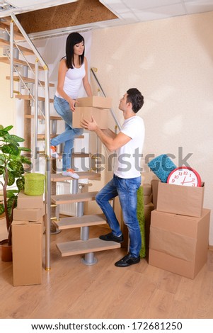 Young couple with boxes in new home on staircase background