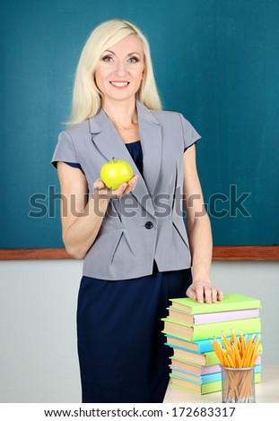 School teacher with apple on blackboard background