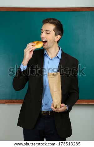 Young teacher with school lunch near chalkboard in school classroom