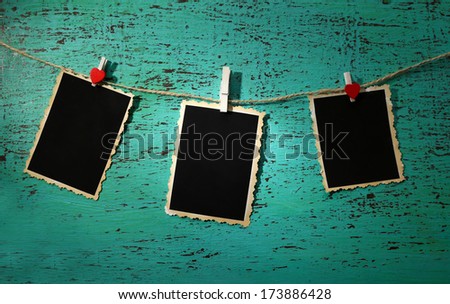 Blank old photos on rope on color wooden background