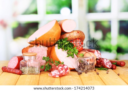 Lot of different sausages on wooden table on window background