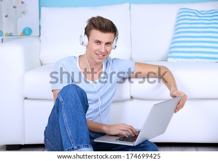 Guy sitting on floor and  listening to music on room background