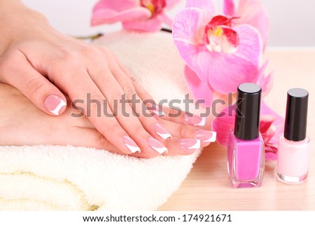 Beautiful woman hands with french manicure and flowers on table close up