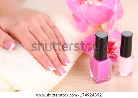 Beautiful woman hands with french manicure and flowers on wooden background