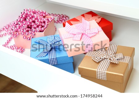 Gift boxes and beads in open desk drawer close up