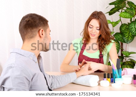 Beautiful girl manicurist doing manicure for man in beauty salon