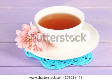 Pink chrysanthemum and cup of tea on wooden table