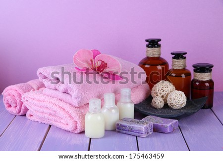 Beautiful spa setting with flower on wooden table on purple background
