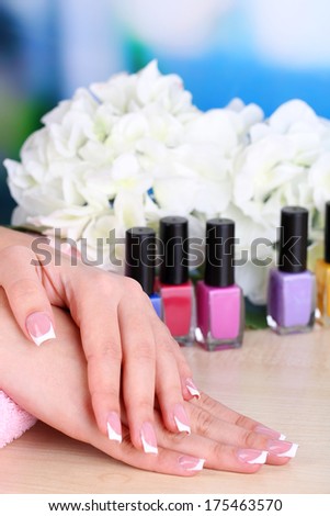 Beautiful woman hands with french manicure and flower on bright background