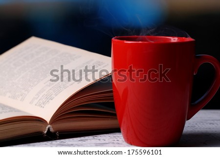 Cup of hot tea with book on table on bright background