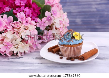 Tasty cupcake with butter cream, on plate, on color wooden background