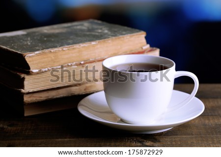 Cup of hot tea with books on table on bright background