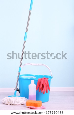 Floor mop and bucket for washing in room on blue wall background
