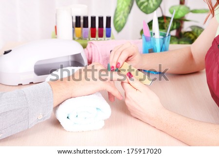 Girl manicurist doing manicure for man in beauty salon