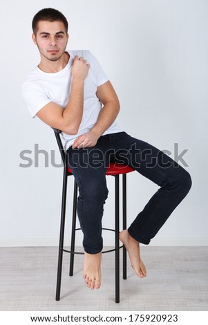 Handsome young man sitting on chair on light background