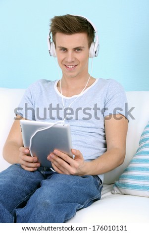 Guy sitting on sofa and  listening to music on blue background