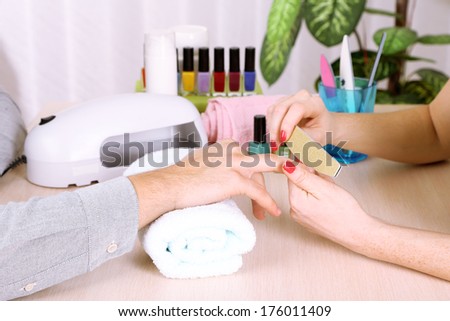 Girl manicurist doing manicure for man in beauty salon
