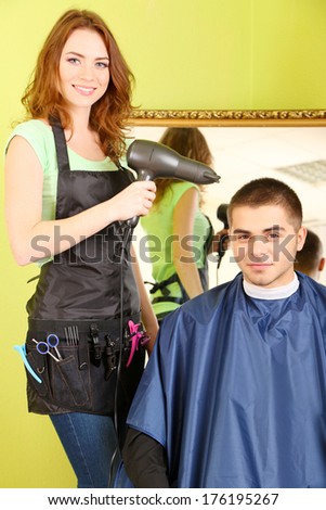 Beautiful girl hairdresser dries hair guy in beauty salon