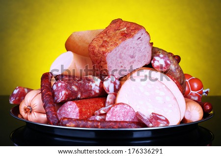 Lot of different sausages on salver on dark colorful background
