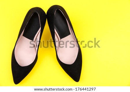 Beautiful black female shoes, on yellow background
