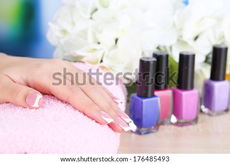Beautiful woman hands with french manicure and flower on table close up