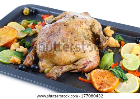 Whole roasted chicken with vegetables on tray, isolated on white
