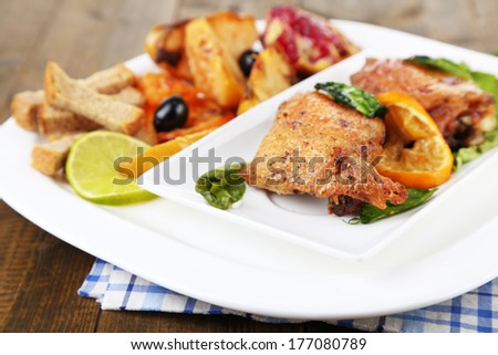 Homemade fried chicken drumsticks with vegetables on plate, on wooden background