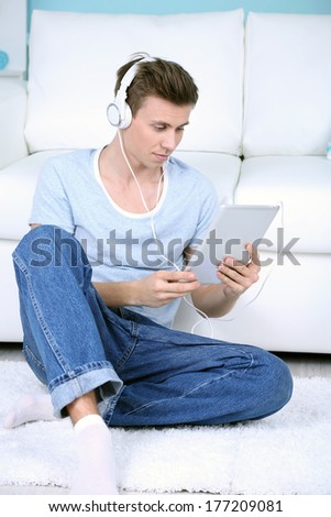 Guy sitting on floor and  listening to music on room background