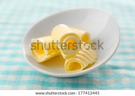 Curls of fresh butter in bowl, on blue tablecloth