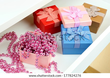 Gift boxes and beads in open desk drawer close up