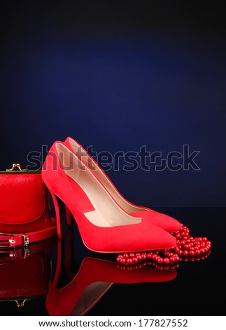 Beautiful red female shoes, purse and belt, on blue background