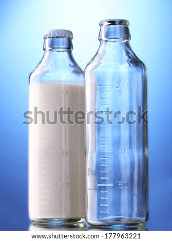 bottle of milk and empty bottle on blue background