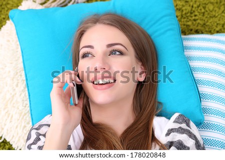 Young woman resting on fluffy carpet with mobile phone, close-up